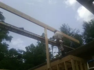 Carpenter setting a ridge beam over a new addition frame — Ice Dam Removal by Roofing Brothers in Paw Paw
