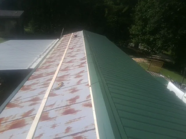 Old rusted panels beside newly installed green metal roofing — Wind Damage Roof Repair by Roofing Brothers in Paw Paw